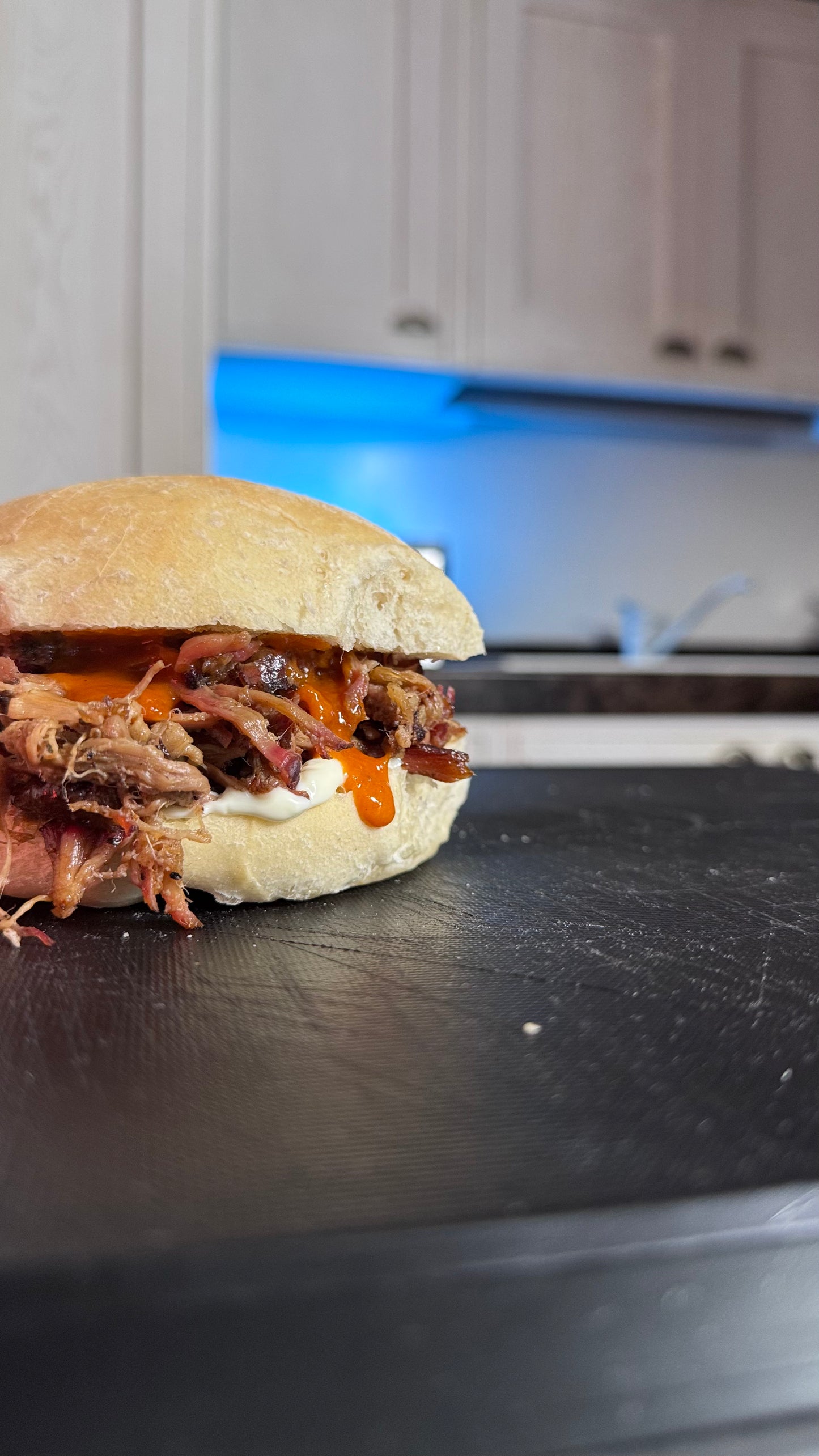 Pulled pork artigianale di maiale affumicato a bassa temperatura in un panino con salsa BBQ e mayo